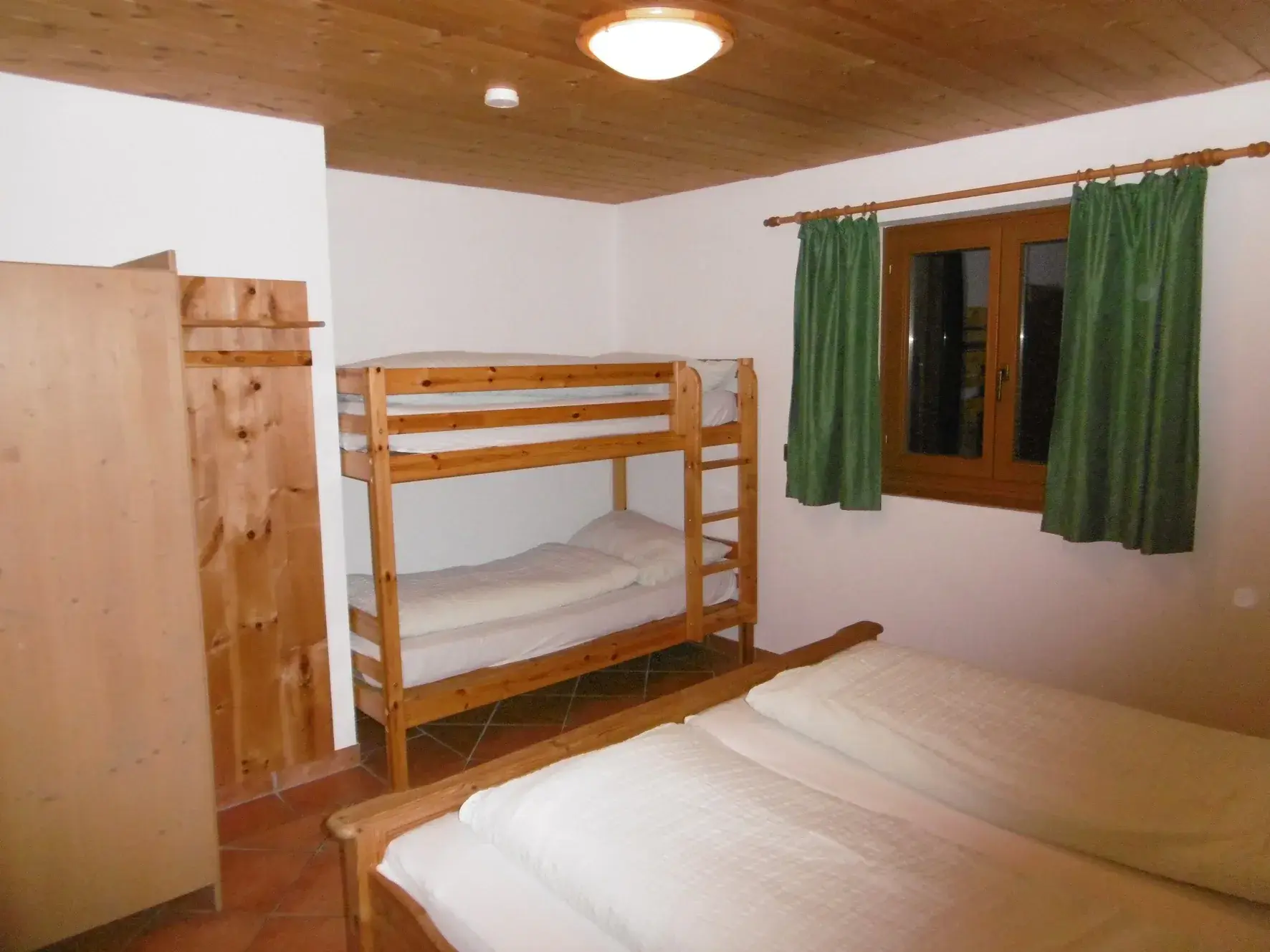 Schlafzimmer mit Doppelbett und Stockbett im Erdgeschoss des Ferienhaus Römerhütte