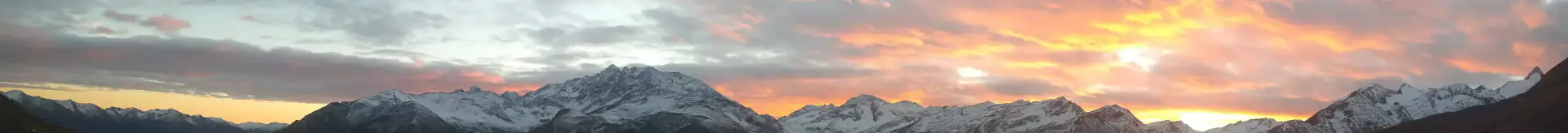 Farbenprächtiger Sonnenuntergang vom Tauerneck mit Blick auf die verschneiten Gipfel des Großglockners, der Schobergruppe und das weite Tal.